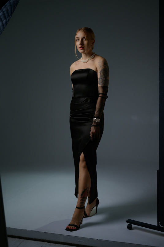 Woman poses gracefully in a glamorous black dress.