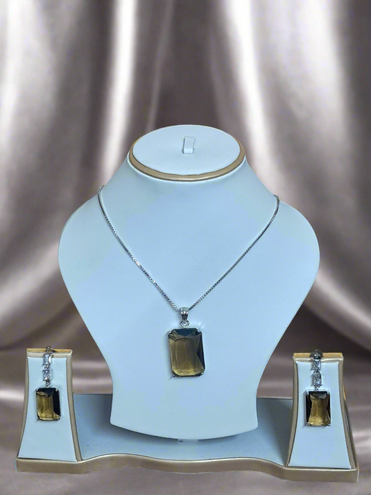Elegant Smoky Yellow pendant set with CZ earrings and silver-plated chain by Garimas, displayed on a jewelry stand.