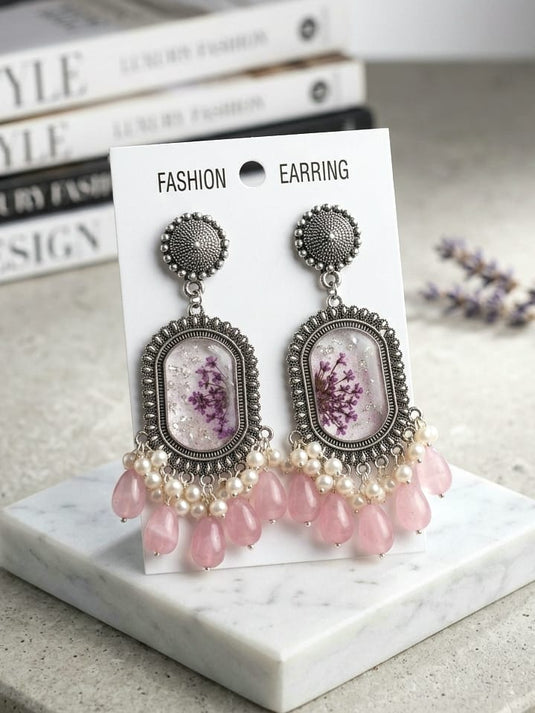 Blush pink floral handmade resin drop earrings with ornate silver-tone frames and bead accents by GARIMAS.