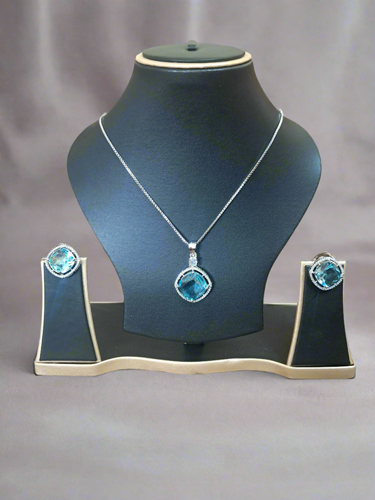 Aqua Blue Pendant Set with CZ studs and silver-plated chain displayed elegantly on a black jewelry stand.