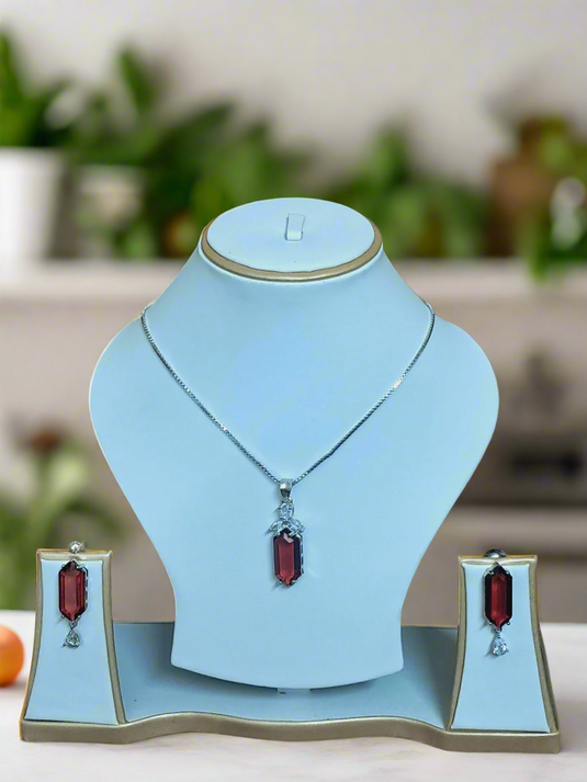 Elegant pendant set featuring a red ruby centerpiece and CZ stones on a silver-plated chain by Garimas.
