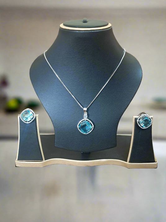 Aqua Blue Pendant Set with CZ studs and silver-plated chain displayed elegantly on a jewelry stand.