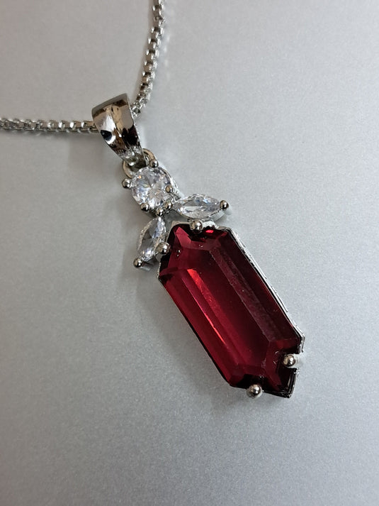 Elegant Garimas pendant set featuring a vibrant red ruby and CZ stones on a silver-plated chain.