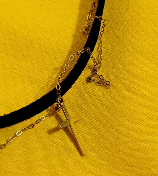 a necklace with a cross on a black cord