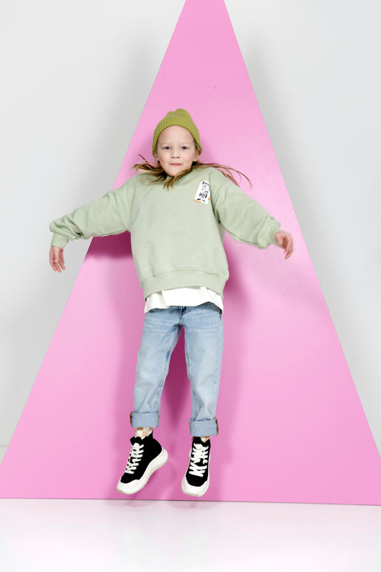 a little girl standing on top of a pink triangle