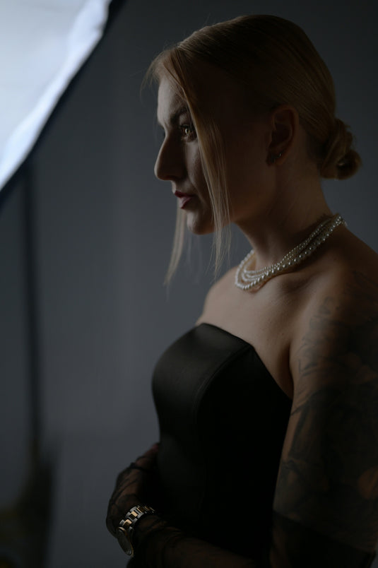 A woman in black dress, profile posing.