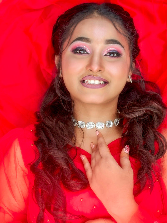 Woman with makeup smiles while looking at the camera.