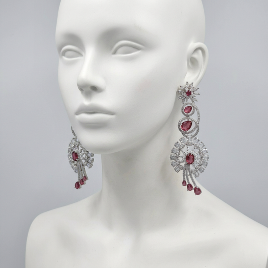 GARIMAS pink floral drop earrings displayed on a white mannequin against a light grey studio background.